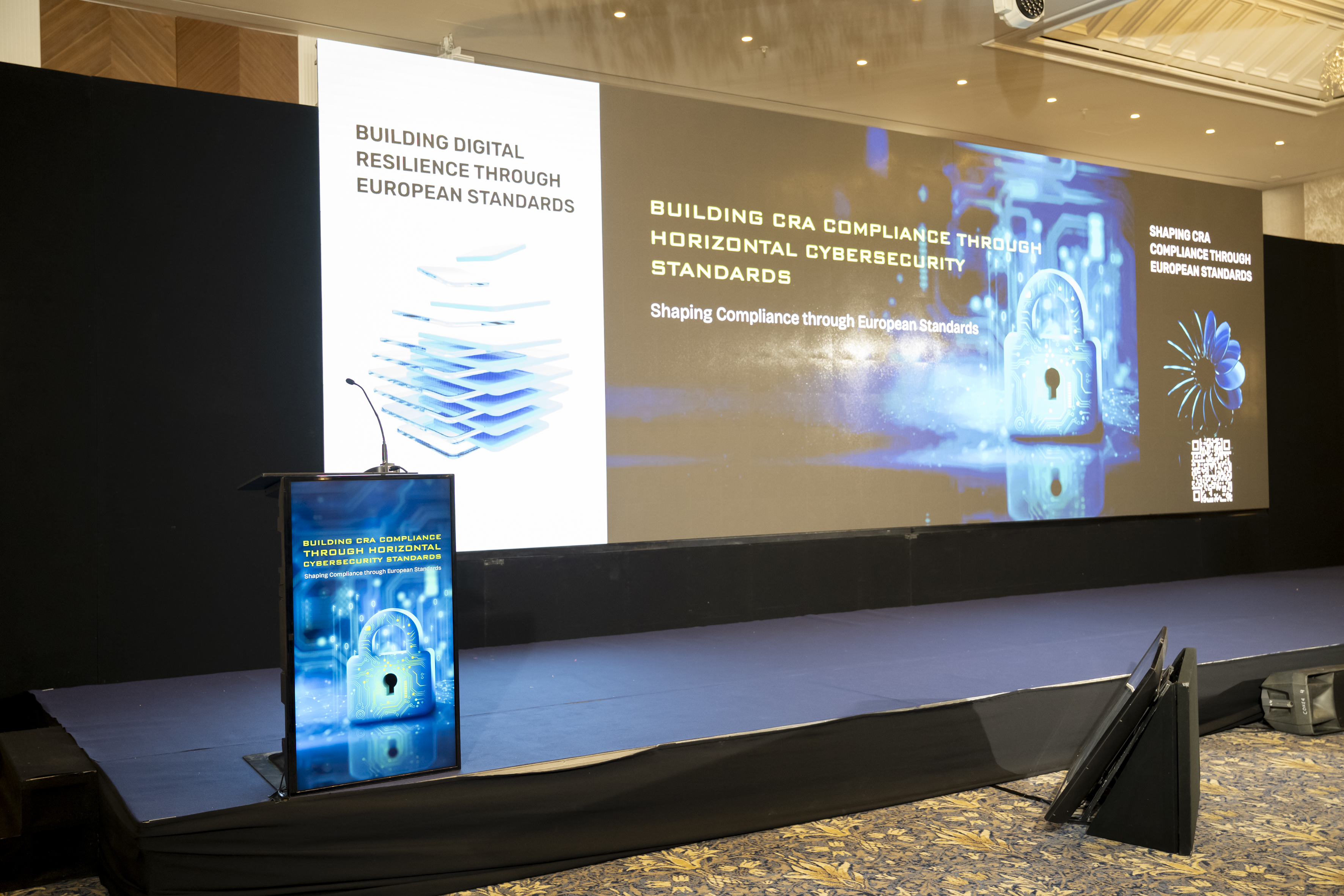 Conference stage and lectern displaying Building CRA Compliance through Horizontal Cybersecurity Standards.
